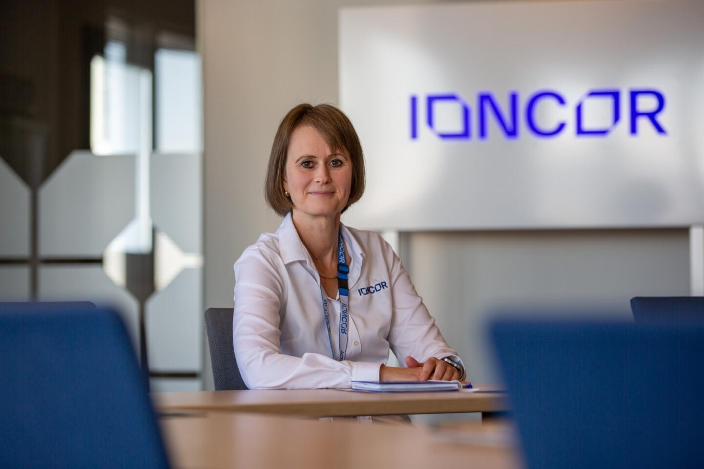 IONCORin sales specialist Johanna Sahla neuvotteluhuoneen pöydän ääressä, taustalla seinällä yrityksen sinivalkoinen IONCOR-logo.